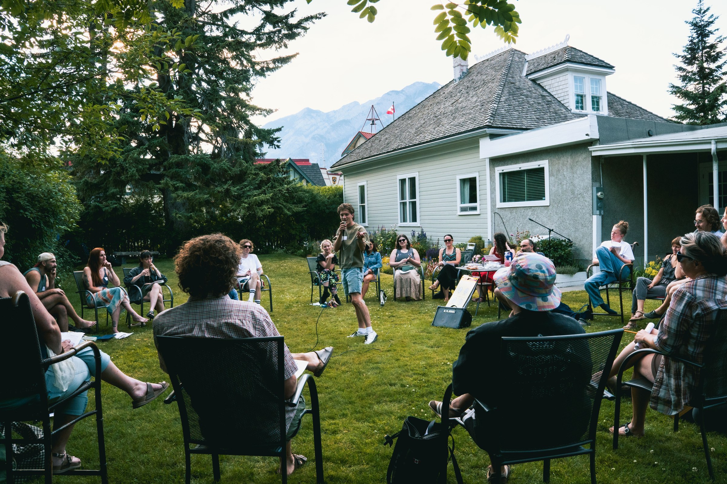 People gathered in a garden listening to a speaker with a microphone
