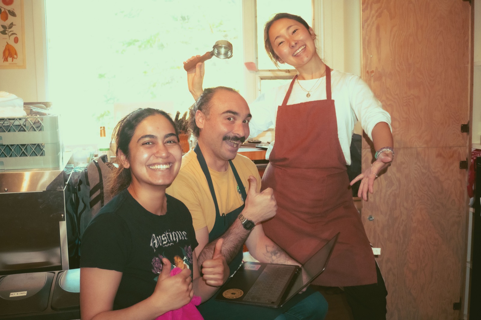 Three smiling café team members behind the counter