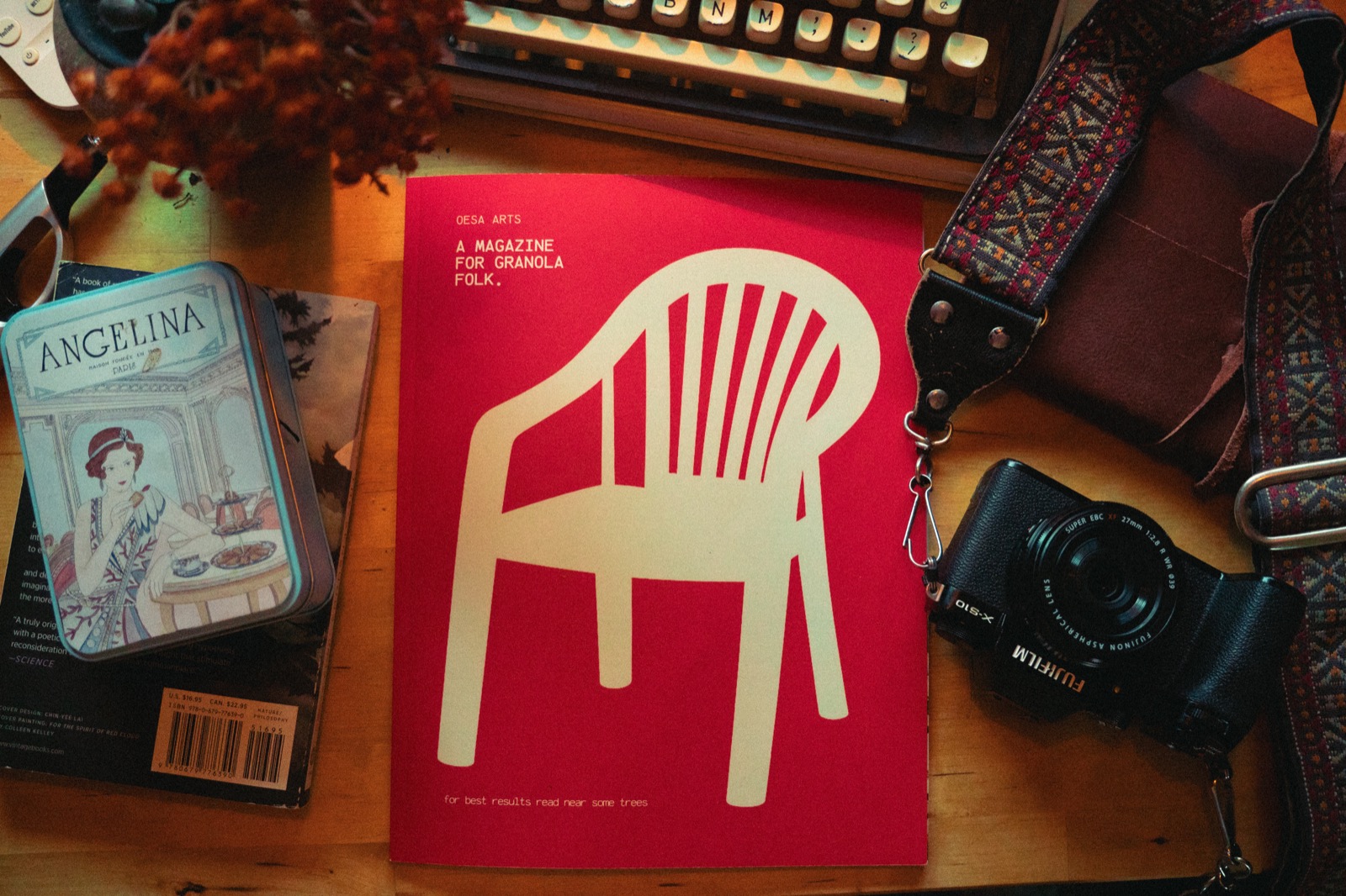 Oesa’s printed magazine beside a camera and typewriter