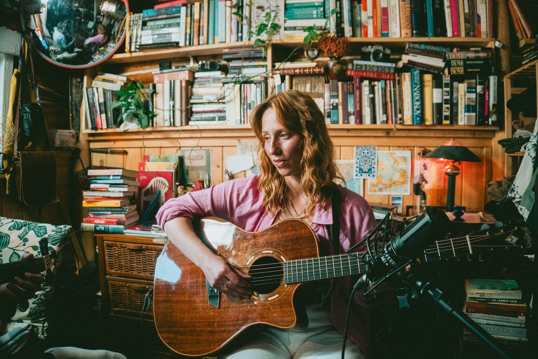 A musician playing guitar in a book-lined room